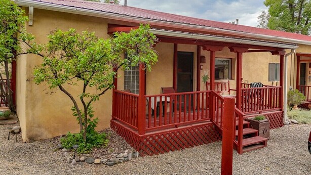 A single-story building with a red porch and a small tree in front.