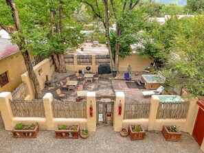 A courtyard with a hot tub, seating area, and a wooden fence.