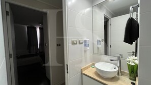 A modern bathroom with a large mirror, a sink, and a towel rack.