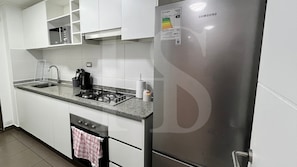 A modern kitchen with white cabinets, a stainless steel refrigerator, a gas stove, and a dishwasher.