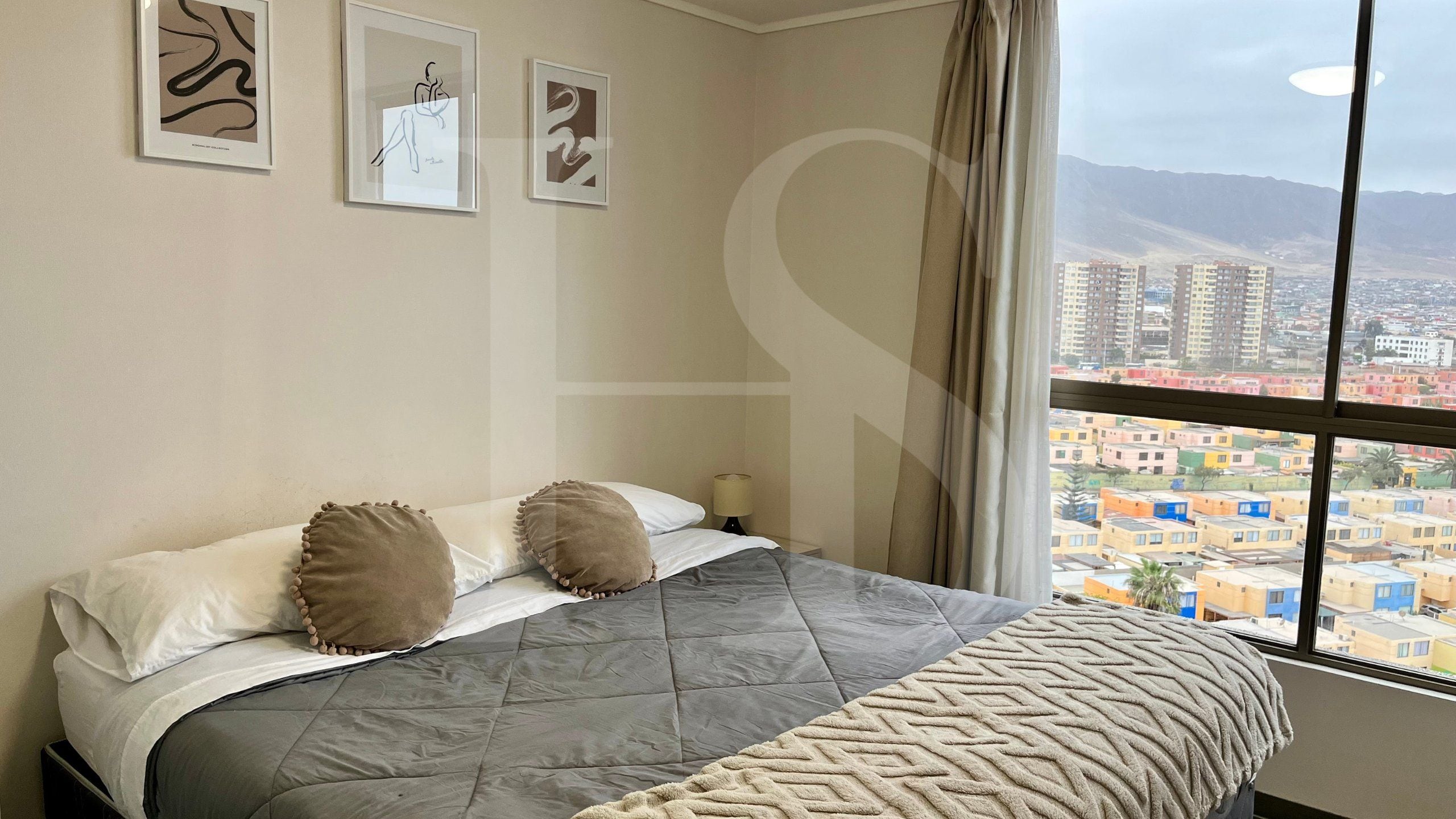 Habitación de hotel con cama, almohadas y un ventanal con vistas a la ciudad.