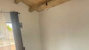 A bedroom with two beds, a nightstand, and a window with curtains.