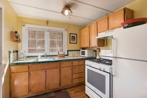A kitchen with wooden cabinets, a stove, a refrigerator, and a microwave.