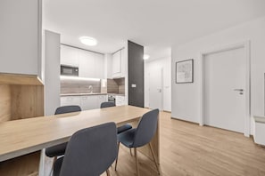 A modern kitchen with white cabinets, a wooden countertop, and a dining area with a table and chairs. - AC 2 room apartment, Old City, Blumentalska (Bratislava)