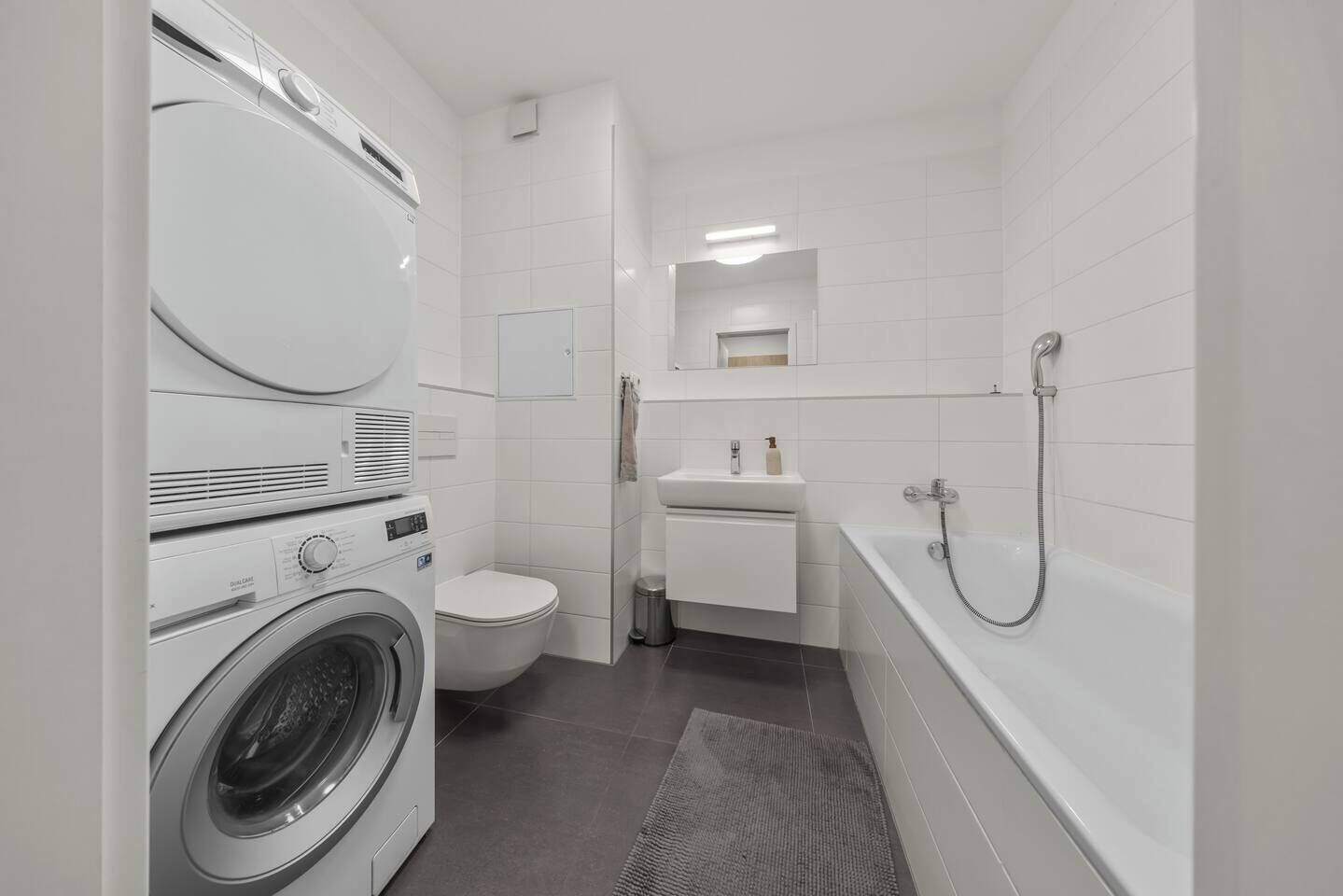 Un baño funcional con lavadora, inodoro, lavamanos y bañera.