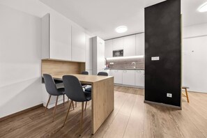 Eine moderne Küche mit weißen Schränken, einem Holztisch und schwarzen Stühlen.