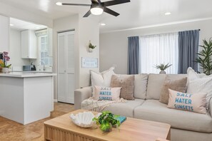 A modern living room with a sofa, a coffee table, and a kitchen area with a counter and cabinets.