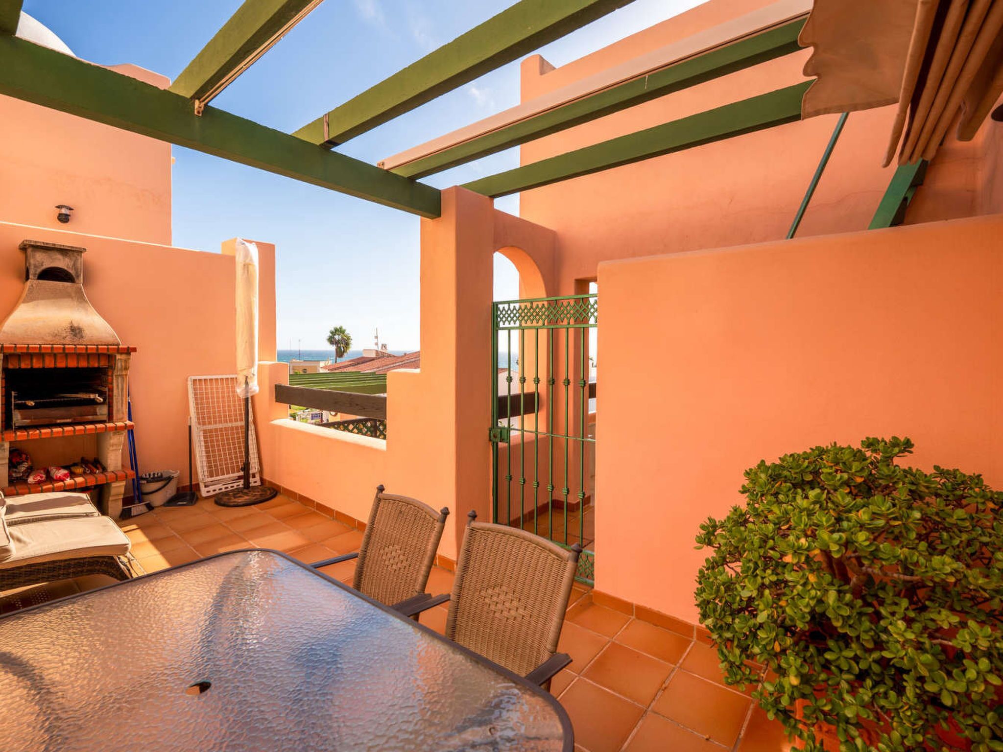 Eine Terrasse mit Grill, Stühlen und Blick auf die Landschaft.
