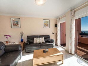 Ett vardagsrum med en soffa, ett soffbord och två inramade konstverk på väggen.