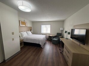 Ein Hotelzimmer mit Bett, Schreibtisch, Stuhl, Fernseher und Fenster.