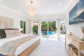 A spacious bedroom with a large bed, a ceiling light, a TV, and a view of a pool and outdoor area. - Fox Eden Resort 8Bd Pool Spa Oasis (Fort Lauderdale)
