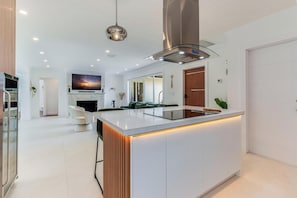 A modern kitchen with a central island, built-in appliances, and a large window. - Fox Eden Resort 8Bd Pool Spa Oasis (Fort Lauderdale)