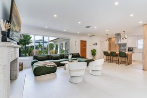 A modern living room with a green sofa, white armchairs, and a coffee table. - Fox Eden Resort 8Bd Pool Spa Oasis (Fort Lauderdale)