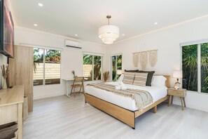 A modern bedroom with a large bed, a desk, and a chair. There are large windows and a ceiling light. - Fox Eden Resort 8Bd Pool Spa Oasis (Fort Lauderdale)