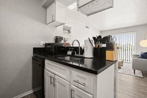 Eine moderne Küche mit weißen Schränken, einer schwarzen Arbeitsplatte und einem eingebauten Ofen.