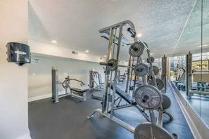 A gym with various exercise equipment, including weight machines and free weights, with a large mirror reflecting the space. - Riverside escape | Pool & Gym | Free parking (Austin)