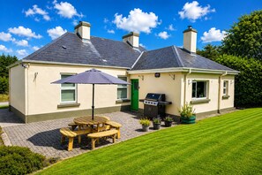 Una casa a due piani con un'area patio, un barbecue e una porta verde.