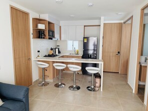 A modern kitchen with a central island, bar stools, and a refrigerator. - Cartagena  Serena del Mar 2 habitaciones, cerca de la playa (Cartagena de Indias)