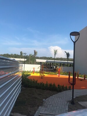 An outdoor exercise area with fitness equipment, a paved walkway, and a building in the background. - Cartagena  Serena del Mar 2 habitaciones, cerca de la playa (Cartagena de Indias)