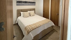 Ein Schlafzimmer mit einem Bett, einem Kopfteil, einem an der Wand befestigten Kunstwerk und einer Tür.