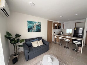 A modern living room with a grey sofa, a coffee table, and a large abstract painting on the wall. - Cartagena  Serena del Mar 2 habitaciones, cerca de la playa (Cartagena de Indias)