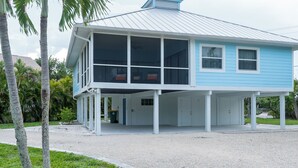 A two-story house with a covered porch and a metal roof. - Sunrise Serenity – Your Sanibel Island Retreat (Sanibel)