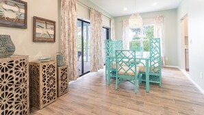 A dining area with a table and chairs, a chandelier, and decorative wall art. - Sunrise Serenity – Your Sanibel Island Retreat (Sanibel)