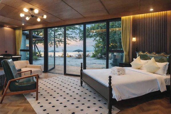 A bedroom with a large bed, a chair, and a view of the beach through large windows. - Room-1 Bedroom Sunset View Villa Koh S (Koh Samui)