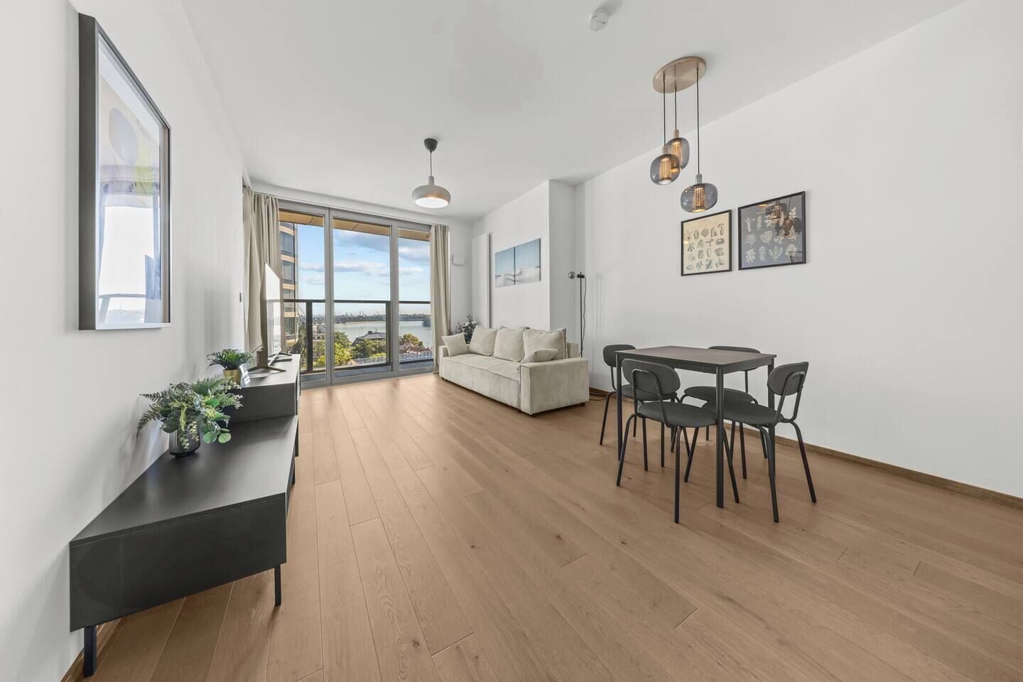 A modern living room with a dining area, large windows, and a view of a body of water.