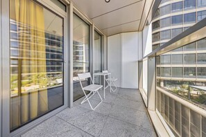 A balcony with a view of a cityscape, two white chairs, and a small table. - Eurovea Tower, Danube View, Balcony & Parking (Ružinov)