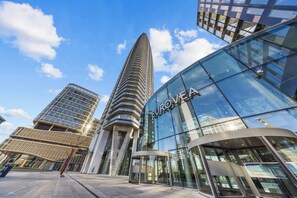 A modern building with a curved glass facade and the name 'EUROVEA' on it. - Eurovea Tower, Danube View, Balcony & Parking (Ružinov)