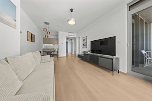 A modern living room with a sofa, a TV, and a dining area. - Eurovea Tower, Danube View, Balcony & Parking (Ružinov)