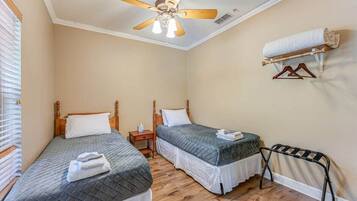 A bedroom with two beds, a ceiling fan, a towel rack, and a wooden floor.