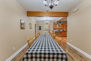 A dining area with a checkered tablecloth, wooden chairs, and a chandelier. - The Chaz Hotel: Chaz River Suite (Homosassa)