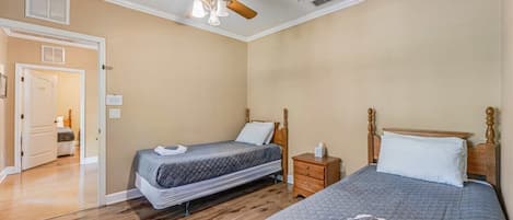 Ein Schlafzimmer mit zwei Betten, einem Deckenventilator und Holzboden.