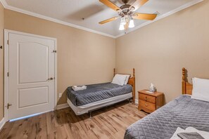 A bedroom with two beds, a wooden nightstand, a ceiling fan, and a door. - The Chaz Hotel: Crystal River Suite (Homosassa)