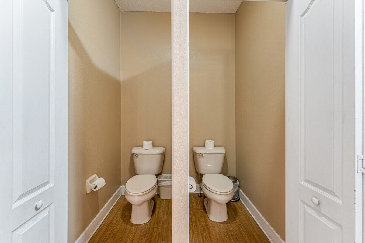 A bathroom with a toilet, a trash bin, and a toilet paper holder.
