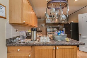 A kitchen with wooden cabinets, a granite countertop, and various kitchen appliances.