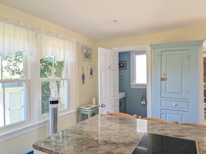 A kitchen with a granite countertop, white cabinetry, and a view of the outside through large windows. - Quaint property right in town (New Shoreham)