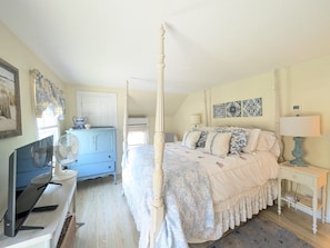 A bedroom with a four-poster bed, a television, a dresser, and a bedside table with a lamp. - Quaint property right in town (New Shoreham)