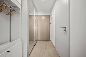 A hallway with a wooden floor, a closet with hanging clothes, and a door leading to another room. - Metropolis Downtown, Balcony, AC & Free Parking (Bratislava)