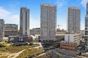 A high-rise building with multiple floors, surrounded by other buildings, and a construction site nearby. - Metropolis Downtown, Balcony, AC & Free Parking (Bratislava)