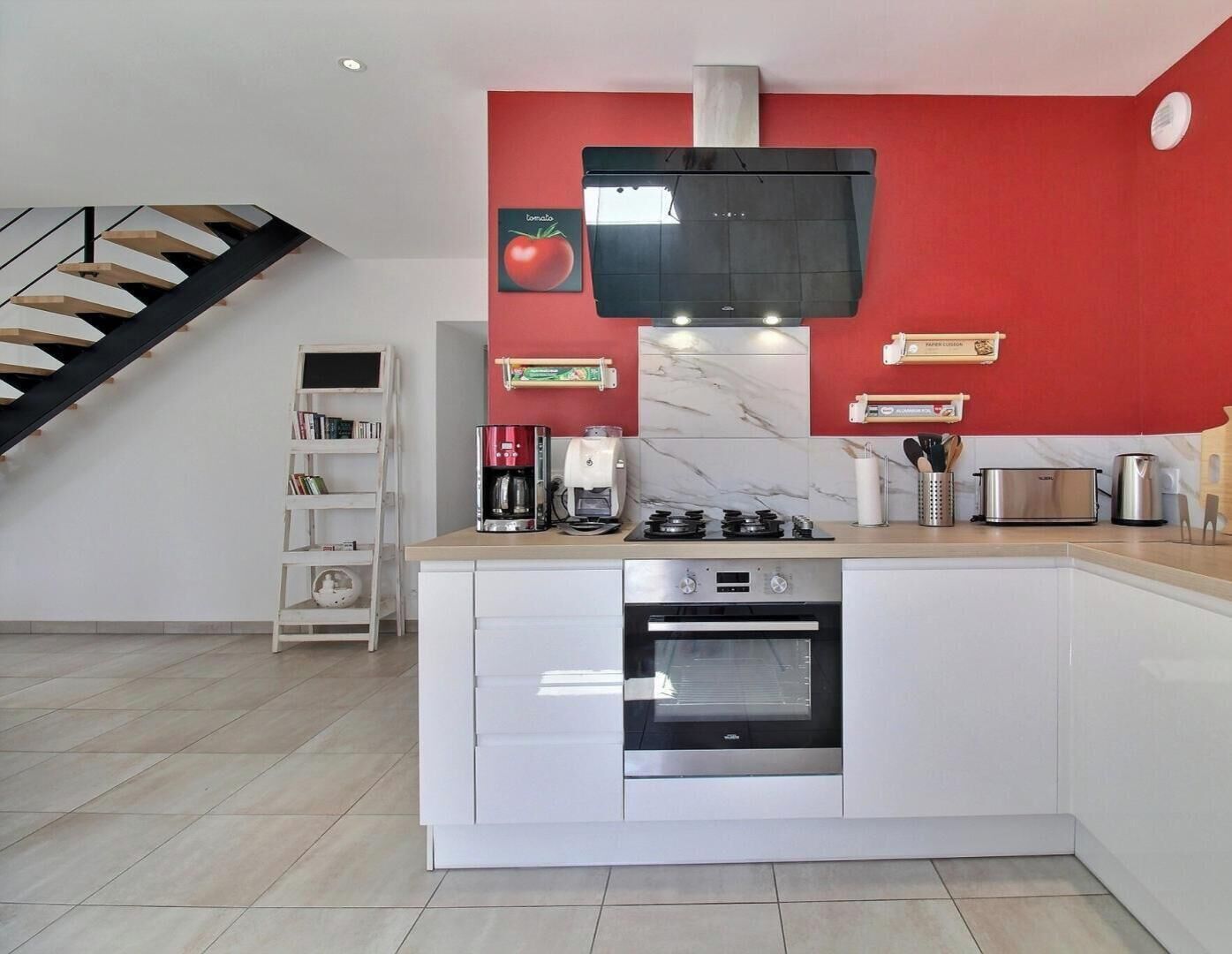Une cuisine moderne dotée d’un îlot central, d’un four encastré et d’un mur d’accent de couleur rouge.