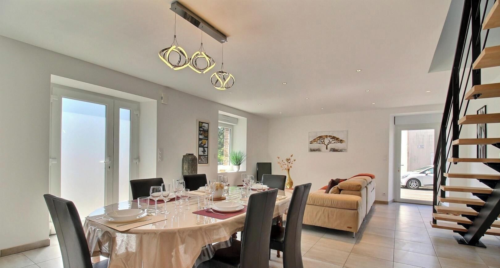 A dining area with a round table, chairs, and a modern chandelier.