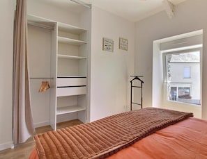 A bedroom with a bed, a wardrobe, a window, and a door. - Le Cocon du Bourg - BAULON (BAULON)