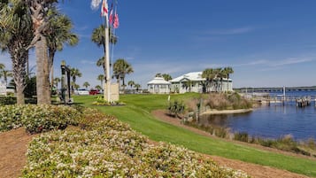 Un campo de golf con un club de campo, palmeras y una masa de agua.