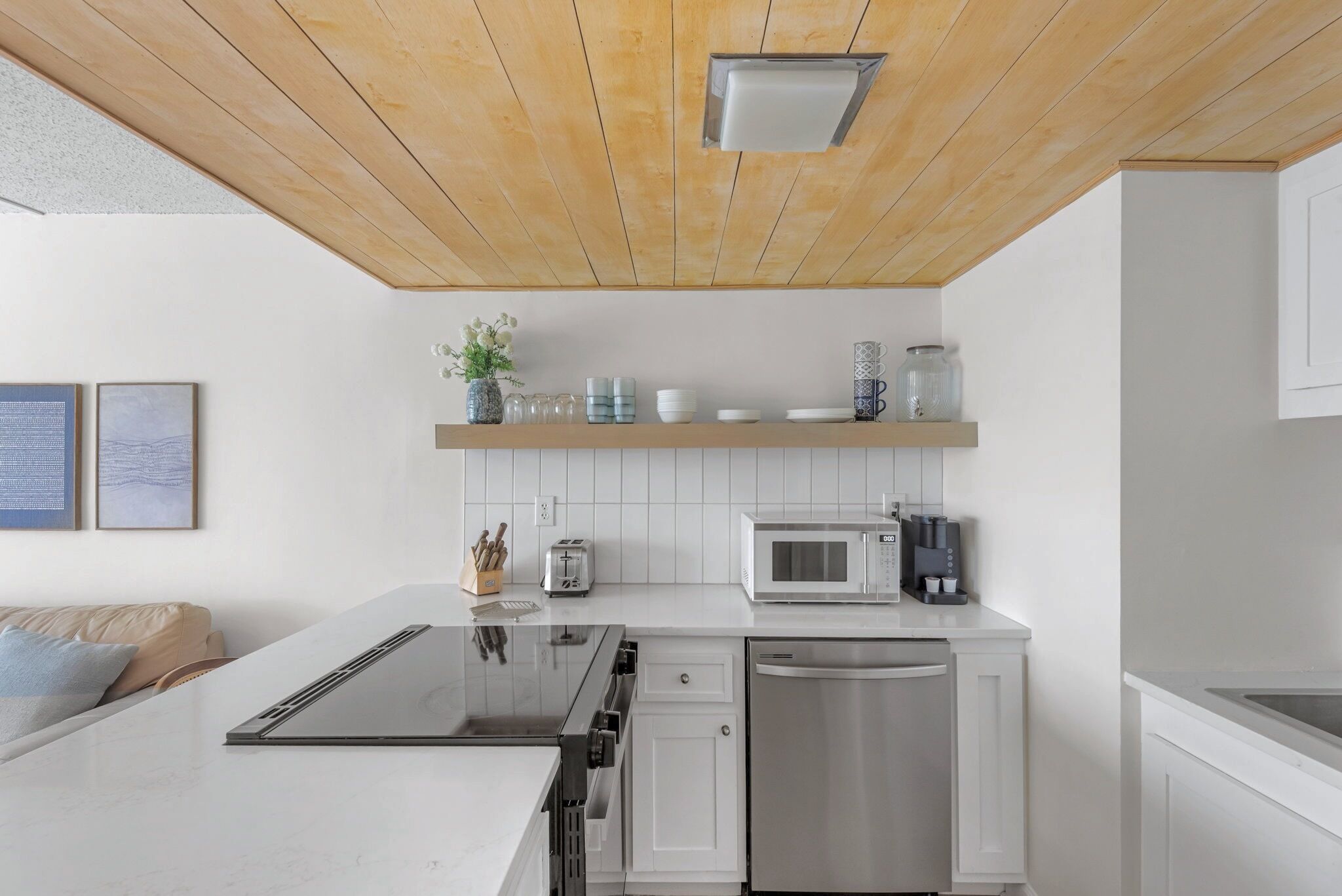 A modern kitchen with white cabinetry, a stainless steel dishwasher, a microwave, and a built-in oven.