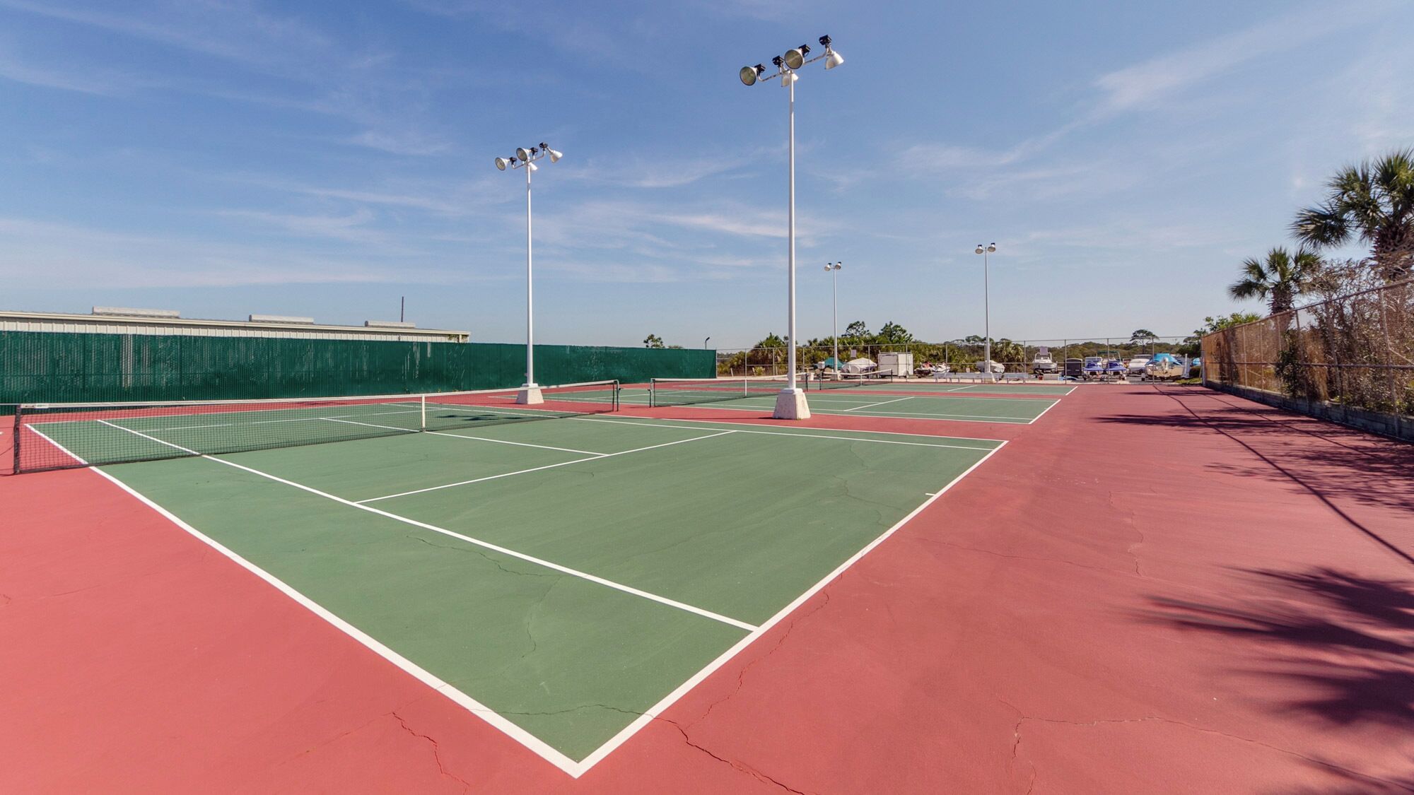 Canchas de tenis múltiples, una valla verde y una pista roja.
