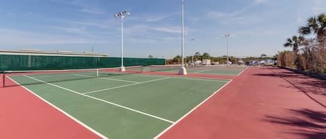 Canchas de tenis múltiples, una valla verde y una pista roja.