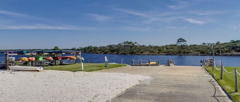 A concrete pathway leading to a dock with canoes and kayaks.